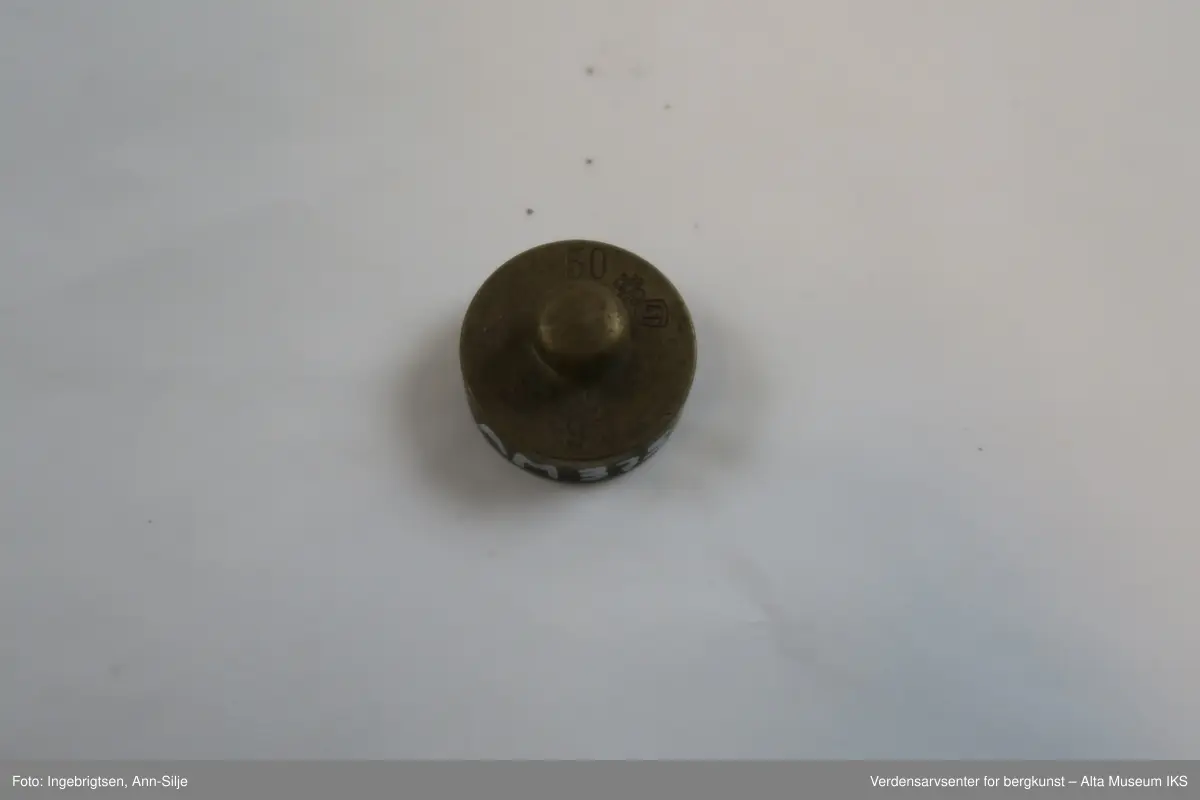 Rektangulær trebit, med hull tilpasset ulike loddstørrelser. Det er 7 lodd: 2 stk. 10 gram, 1 stk. 20 gram, 1 st. 50 gram, 2 stk. 100 gram og 1 stk. 200 gram. Alle loddene er sylinderformet med knott på toppen. Loddene varierer i størrelse: de minste er 2 cm i diameter og 1 cm i høyde, mens den største er 4 cm i diameter og 2,8 cm i høyde.