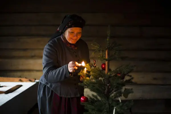 Kvinne tenner levende lys på juletreet.