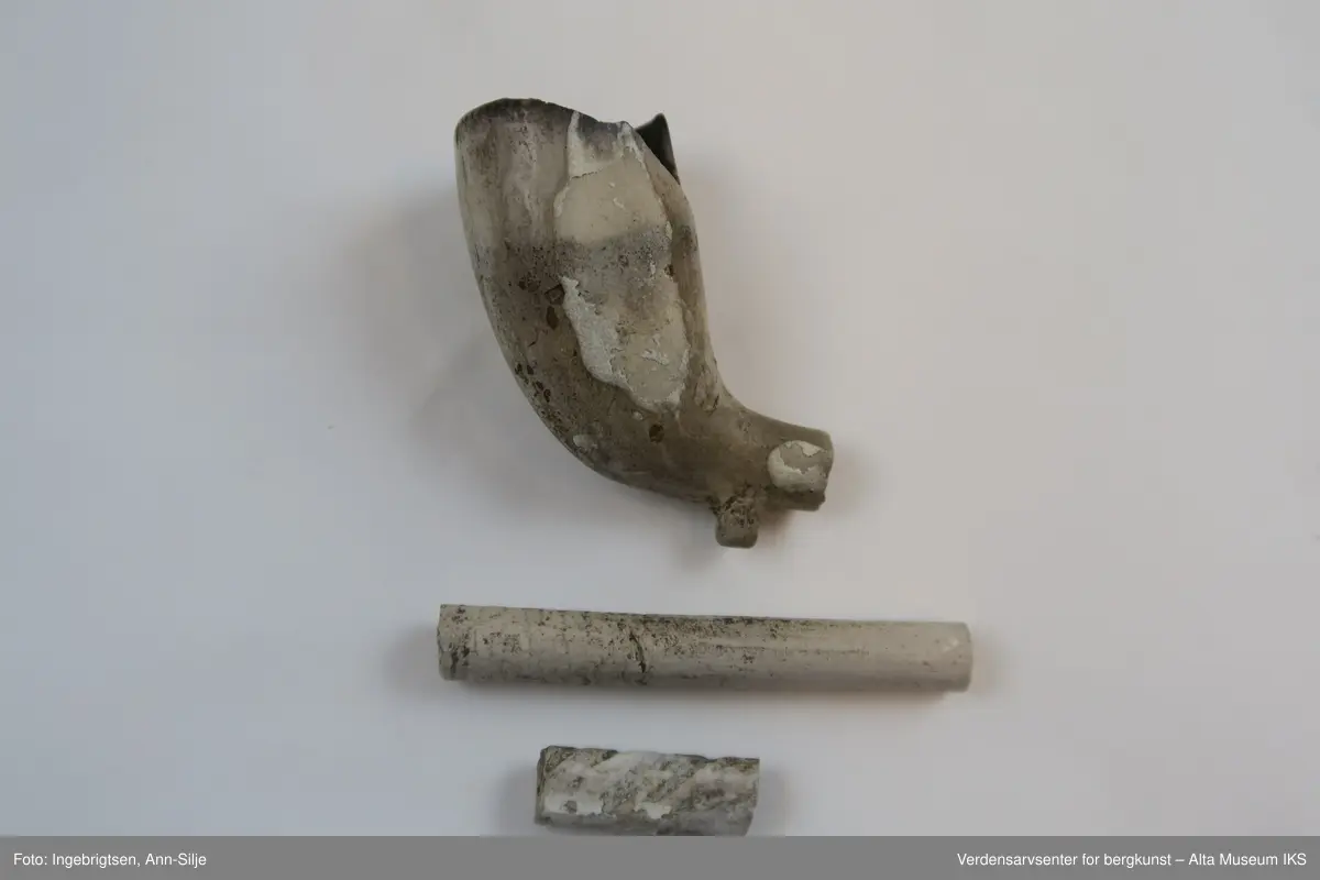 En samling fragmenter av krittpiper. Et av pipehodene er mer eller mindre hel, men med avbrukket pipehals. 

Fragmentene varierer i størrelse fra 1,5 cm til 5,7 cm i lengde og 0,5 cm til 2 cm i bredde.
