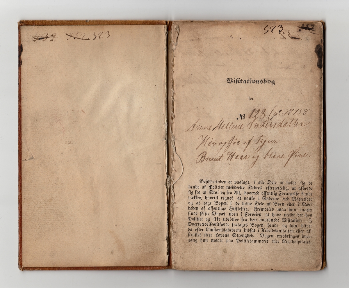 Lysebrun notisbok med gulldekor. Boken har flere registreringsnummer som er overstrøket, 432, 352, 523. Det ser ut til at det originale registreringsnummeret har vært 128. På bokens sider er det notert datoer for visitt med politilegens signatur.