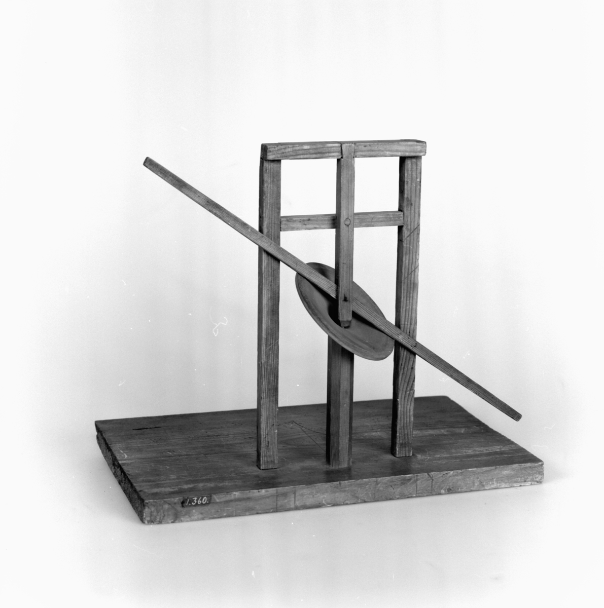 Modell ur Polhems mekaniska alfabet. Text på föremålet: "LXIV". Vid rotation av den lodräta axeln erhålles med hjälp av den vinkelställda skivan en vickande rörelse hos armen.