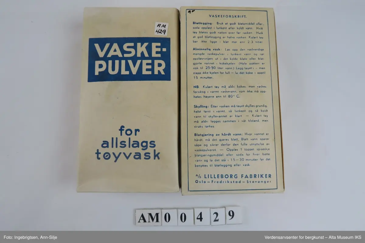 Hvit rektangulær pakke med pulver. Øverst på pakkens forside er det et blått felt med hvit skrift. Ellers er det tekst i blått skrevet på alle sidene på pakken.