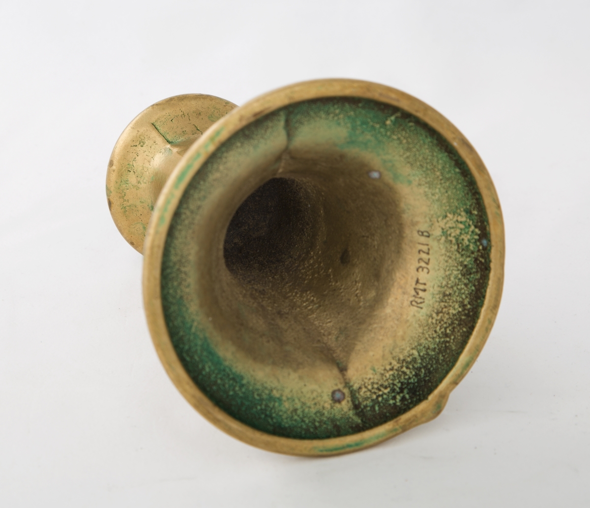 Rund sokkel, slank utføring. Dekorert med to riller på sokkel, og to riller på skaftet. Vider seg ut ved lyspipen.