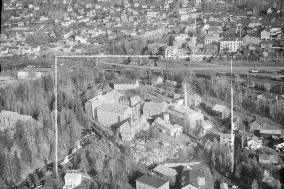 Flyfoto, Lillehammer, Gudbrandsdalens Uldvarefabrik AS, (ca.1951), mot Lillehammer sentrum. Jernbanestasjonen til høyre og jernbanen tvers over midten av bildet. Positivkopi med samme nr. 30688 har et annet motiv av fabrikken.