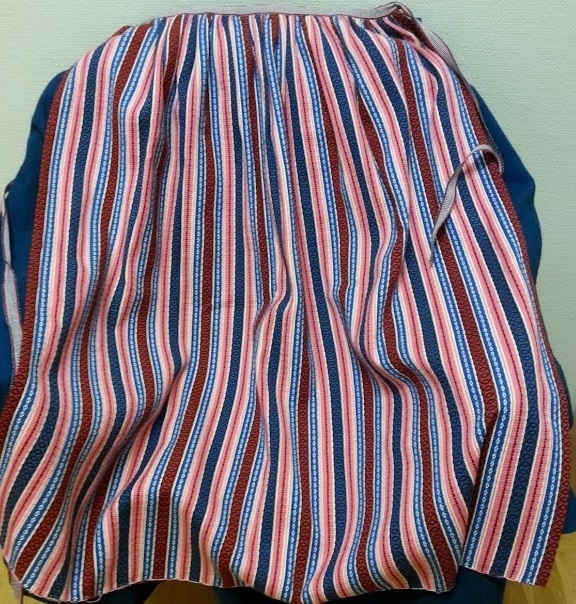 Hembygdsdräkt från Breared,Halland.
SKJORTA i Linneväv Handsydd med lingarn och med broderad smock på handled och överarm med röd och vit bomullsgarn. broderi på krage och knäppslå.
LIVSTYCKE: Handsytt Yttertyg Handvävt i rosa och blå opphämtaränder på blekt tuskaftsbotten. Blekt linnefoder.
KJOL: Handsytt i blå tuskaftsylle, 3 meter i omkrets med smockveck i midjan från - höftkam - bak - höftkam.
Linning knäppe fram.
FÖRKLÄDE: Handsytt av Handnävt i rosengång med rosa, blått och vitt bomullsgarn.
SJAL: 1/2 Fyrkant delad på tvären.Handvävd i tuskaft med blått Bomullsgarn .
Broderad mit bak med silketråd i rosa,grön mm.
HÄTTA: broderad med silkegarn på blått sidentyg och monterad på mjuk stomme.
KJOLVÄSKA: Handsydd av röd ylleväv,fodrad med oblekt linneväv, blå -grönt band runt ytterkant och monterad med silverbygel, broderad med blå,gul,vit ullgarn,