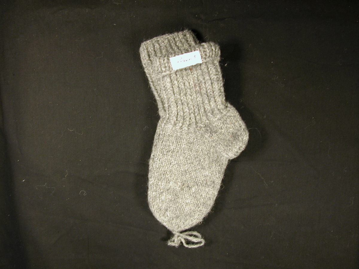 Et par ullstrøpmer til barn i grått ullgarn. Fremstår som ubrukt.