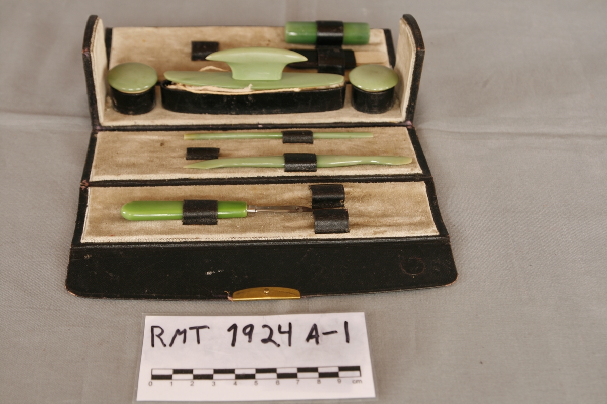 Manikyrsett med opprinnelig tolv deler i tillegg til etuiet. Etuiet har en kjerne av papp, dekket av kunstig skinn. Trykklås av metall. Etuiet kan brettes helt ut, endeveggene er stive. Innsiden har dekke av lys brungrønn fløyel, hver side har holder til tre deler av manikyrsettet. Jadegrønn finish på de ulike manikyrdelene.