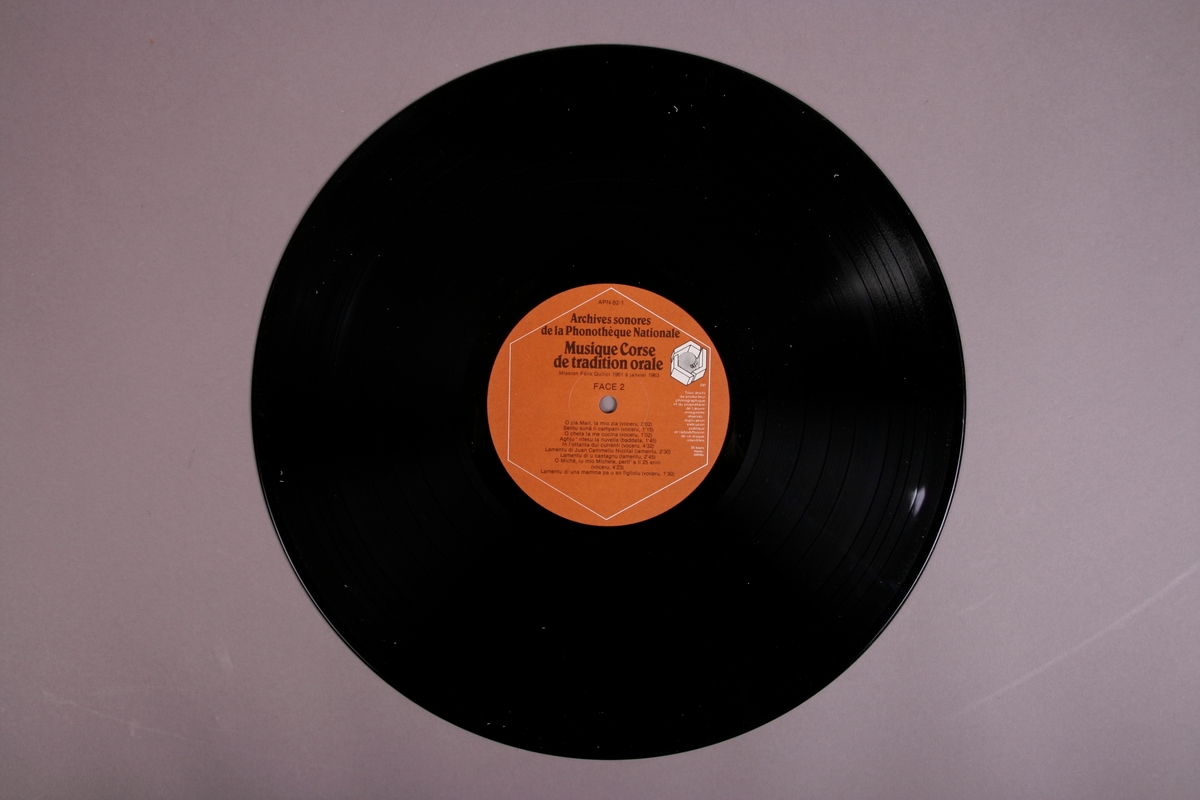 Plateomslag i form av en eske i oransje stoff, tre grammofonplater i svart vinyl som ligger i papirlommer, samt et hefte. I tillegg et klistremerke inne i  esken.