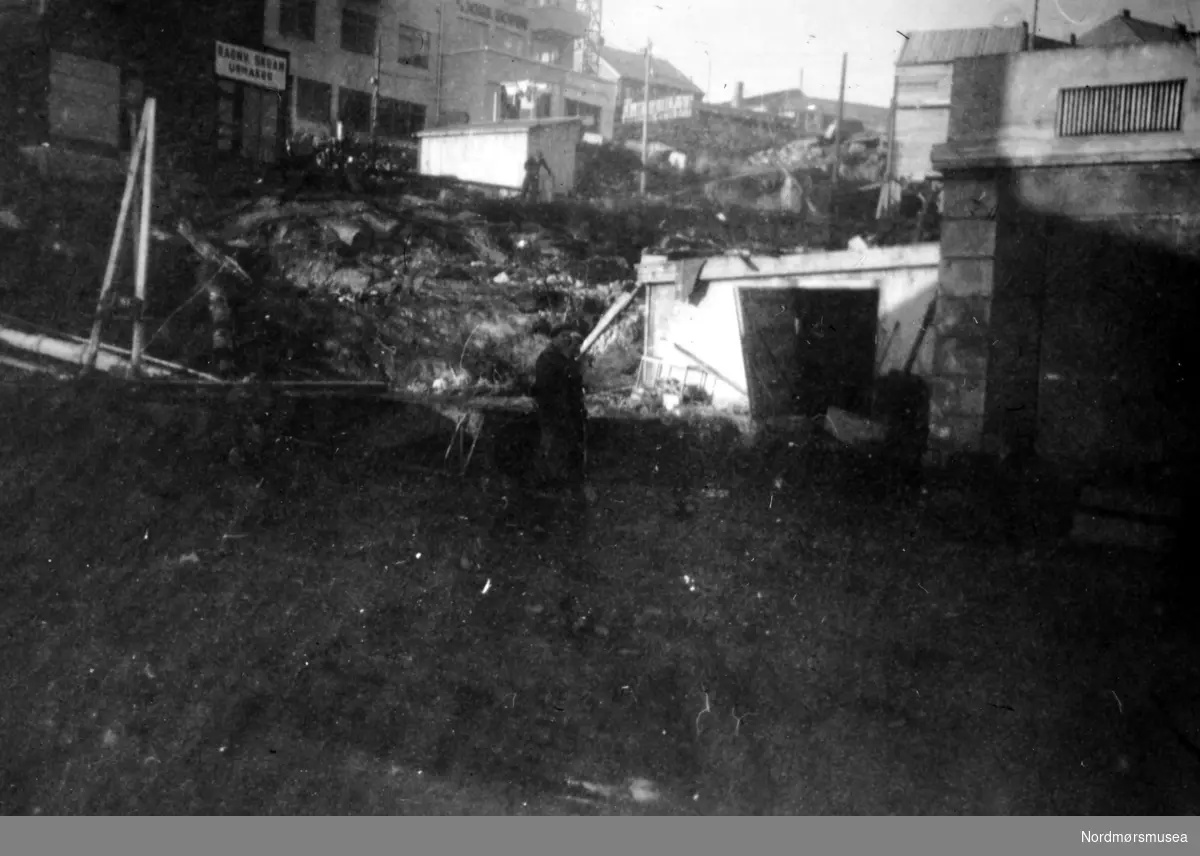 Grunnarbeidet til det nye rådhuset i Kristiansund er i gang, nord for Loennechengården. Bildet er fotografert fra Sør-øst, over fra Fisketorget og Kaibakken. Rådhuset ble ferdig oppført i 1953, og arkitektene bak bygget var Molle og Per Cappelen, som vant konkuransen om oppføringen av rådhuset i 1947, med omkamp-konkuranse i 1948. Bygget er reist på armert betong i to volumer: En kontorfløy og en bystyresal, med det hele på en sokkeletasje. Nordmøre Museum: se flere bilder i samme serie