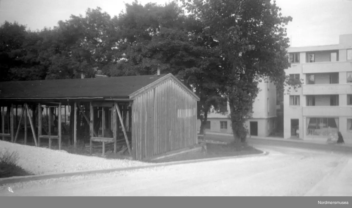 Knoblochs rammeverksteds brakke ved Roligheten (ovenfor den seinedre Kirkelandets kirke 1963), i Peter Rosentræders gate. Nå rives den, sammen med de andre brakkene i Roligheden. Det ble lekeplass her. I bakgrunnen ser vi Langveien og Damehjemmet/seinere Frimurerlosjen. Bildet er datert oktober 1953. Nordmøre Museum