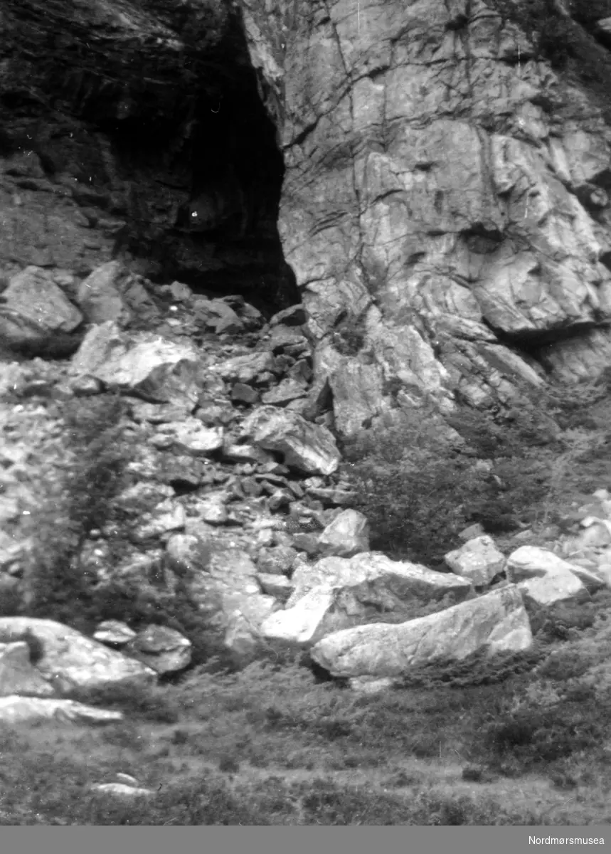 På bildet ser vi Bremsneshula, fotografert nede fra foten av hulen. Inngangen kan sees øverst fra steinrøysen. Bildet er datert ";en solmørk dag"; i juli 1954. Se mer informasjon i Yderstads notater, bind 10 side 58. Fra Nordmøre Museums fotosamlinger.
