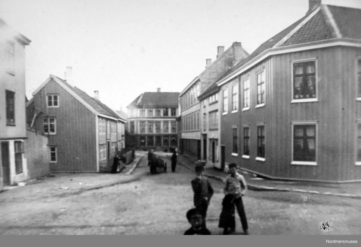 "Øvre Gade". Foto fra deler av bebyggelsen i Øvre Gate på Kirkelandet i Kristiansund. Bildet er fra fotoalbumet "Christiansund i Fotografier". Bildet er trolig fra 1883 etter informasjon fra Willhelm Lund samlingen. Fra Nordmøre Museums fotosamlinger. 