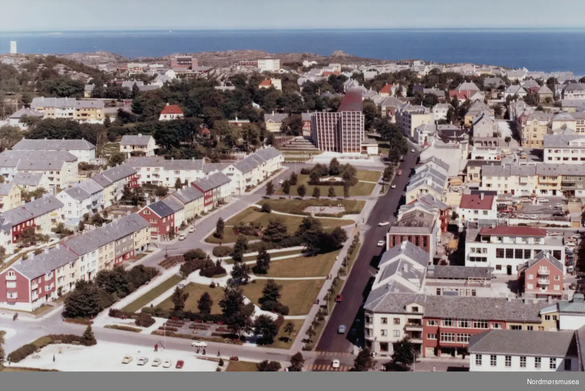 Flyfoto fra Parken og Roligheten med Kirkelandet Kirke i bakgrunnen, på Kirkelandet i Kristiansund. Flyfotoet er utført av Widerøes flyveselskap den 17. juli 1965. Fra Nordmøre museums fotosamlinger. Reg: EFR
