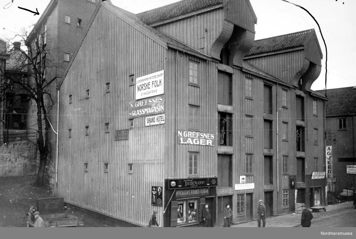 Foto fra Storkaia 4, hvor vi ser N. Grefsnes glassmagasins lager, Nykaiens Frukt og Tobak, A. Gjerde, samt M &amp; Didrik Williamsen, som hadde lokaler i Storkaia 1. Huset like bak Storkaia 4 er Storgata 11. Fra Nordmøre Museums fotosamlinger.
