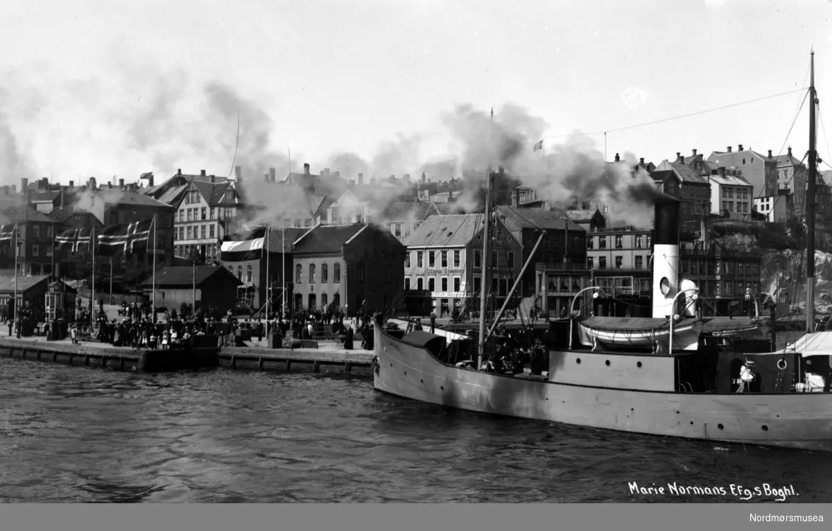 Postkort fra Kirkelandet allmenning på Kirkelandet i Kristiansund, hvor vi ser en større dampbåt fortøyd ved dampbåtkaia. I bakgrunnen ser vi deler av Fisketorget samt blandt annet Tollboden og Jonas Eriksens skipshandel. Fotograf og datering er ukjent, men kan være Georg Sverdrup, mens datering er sannsynligvis fra perioden 1910 til 1920. Kortet er utgitt av Marie Normanns Efg. bokhandel - senere Sverdrups bokhandel. Fra Nordmøre Museums fotosamlinger.