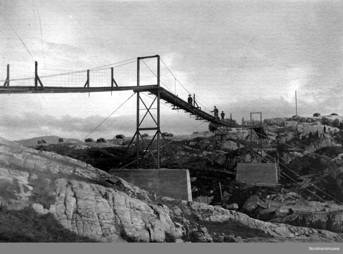 Brua over fra Bentnesset til Meløya. Denne hengebrua og brua over fra Meløya og til Skorpa var Kristiansunds første bruer og ble bygget i 1910.
(ALTERNATIVT BILDE: KMb-1987-005.0733)
Brua over sundet mellom Bentnesset og Meløya; hengebrua som ble bygget i 1910.  Bruforbindelsen for Meløya og Skorpa var et gammelt ønske. I 1910 ble det vedtatt å bygge en permanent jernbru over Skorp-sundet, og over Dunkarsundet en hengebru, som av hensyn til båttrafikken måtte legges 11 m over flomålet. "Hængbroen kalder folk "et mirakels" og jernbroen er "stø som stuagolve»," het det da de var fullført. 22/10-1910 skriver TK: "Rossings hængbro er nå ferdig og igår foretos belastningsprøve. Denne bestod deri at broen belastedes med sandsække, som tilsammen veiede 15 ton eller 15000 kilo. Prøven falt tilfredsstillende ut. Nå står kun tilbake at ordne ved selve veiforholdet, for at få opgangen til broen lettere. Når den er fullført, har Meløens beboere faat sit forbindelsesledd med selve hovedøen. Andersens jernbro som forbinder Meløen med Skorpen, er også fullført. Alt i alt er 2 arbeidsstykker her utført, som der står respekt av. Særlig Rossings hængebro er imponerende. Forrige søndag var der en livlig trafik til Bængtnæsset av interesserede tilskuere, og alle var forbauset over hængebroen, særlig syntes mange den var svimlende høi over sjøen ( 11 meter over flomålet). Denne høide er imidlertid påbudt av havnevæsenet for at fartøier med rig skal kunne passere under den. (Den nye brua ble farbar for folk i området fra høsten 1939. Kjørbar var den ikke før i mars 1940 iflg. TK.)


---Brua over fra Bentnesset til Meløya. Dene hengbrua og brua over fra Meløya og til Skorpa var Kristiansunds første bruer og ble bygget i 1910.

KITTY WILLIAMSEN tok initiativet:

Kjære du fru Kitty W

du som er i bystyre'

du som snart er hele byens pott og panne.

Du som skaffet oss ";Presto";:

hjelp oss så vi får en bro

som fra Skorpa fører bort

til Gomalandet.

Dette diktet har stått i lokalavisene flere ganger, og må være fra ca. 1910. Det har vel mer preg av bønn enn av hyllest, og ønsket gikk i oppfyllelse: Den første hengebrua til Skorpa ble laget på Kristiania Spigerverk 
for kr. 5000,-. Den var i bruk til 1938.

Arnulf Johnsen var en flittig bidragsyter i Romsdalsposten utover 1900-tallet, og han brukte gjerne opp igjen formuleringer han syntes han hadde fått godt til, når samme sak skulle omtales på nytt. Slik brukte han å innlede minneartikler om Kitty Williamsen: 

";Da kvinnene i vår by marsjerte inn i samfunnslivet for å styrke det i dets mangeartede gjøremål og likestilling med mennene, var det fru Kitty Williamsen som gikk i spissen og ble den selvskrevne fanebærer. Takket være kvinner av hennes støpning er et imponerende arbeide blitt utført for kvinnenes likestilling i samfunnslivet. Og våre kvinner av i dag må føle dyp takknemlighet mot de kvinner som gikk i bresjen for kvinnenes frigjøring.";

Hun ble født 3. august 1864 på Varteig prestegård (nå Sarpsborg kommune) som Christiane Andersen (navnet Kristine er også brukt), og var datter til sokneprest, tidligere skolebestyrer Anders Andersen (1812-1868) og Hedvig Helene Johanne Bay (1822-1894). Hedvigs mor var Maren Cathrine Ulsriksdatter Hals, og Kitty tok med familiens samtykke dette etternavnet. Hennes bror Fridtjof Sebastian Hals (1868-1895) ble døpt Hals. De var åtte søsken. 

(Fra Nordmøre museums fotosamlinger)