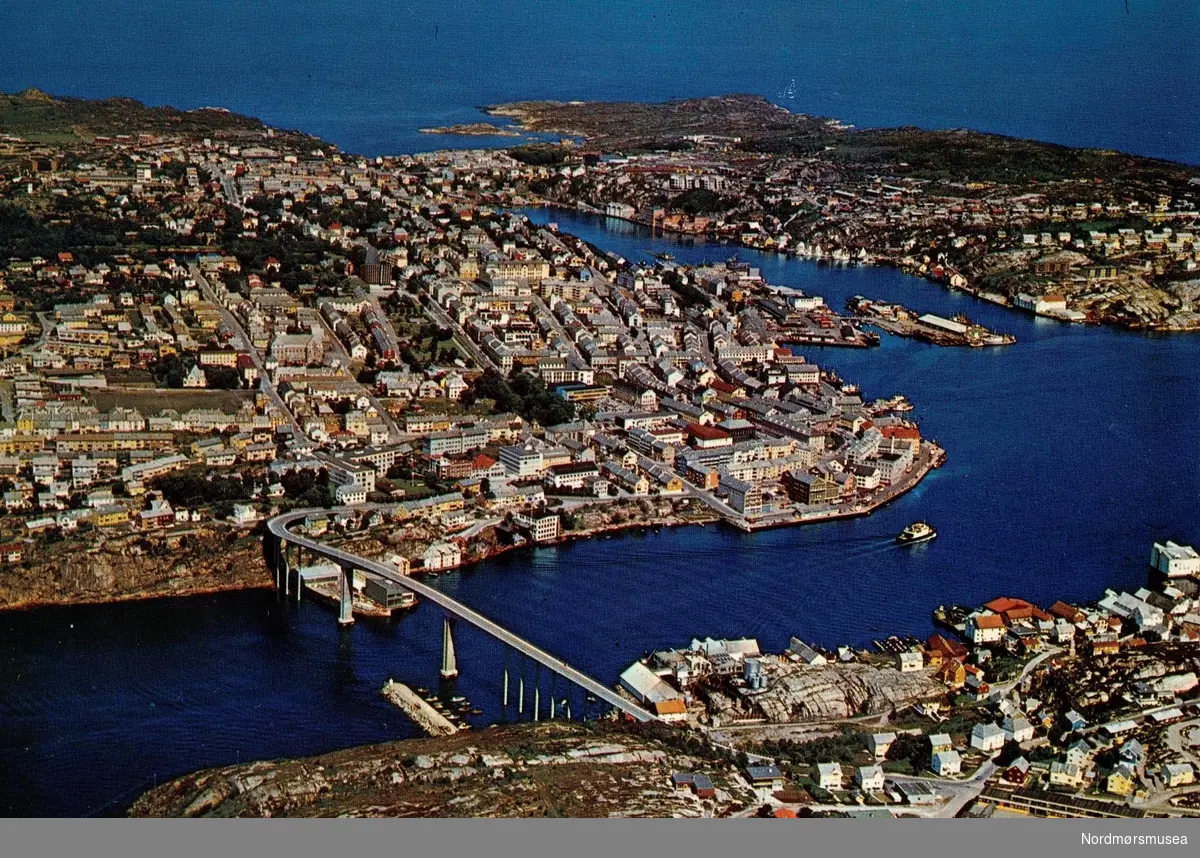 Postkort ";2568/18"; med flyfoto fra Kristiansund. Her ser vi tre av byens fire land. Helt i forgrunnen ser vi Innlandet, mens til venstre ser vi Kirkelandet. Det er Sørsundbroen som knytter disse to landene sammen over Sørsundet- Ellers så ser vi Gomalandet til høyre i bildet. Det fjerde ";landet"; som ikke er kommet med på bildet er Nordlandet. Kortet er utgitt av Mittet &amp; Co. A/S. Fra Nordmøre Museums fotosamlinger. Reg: EFR

