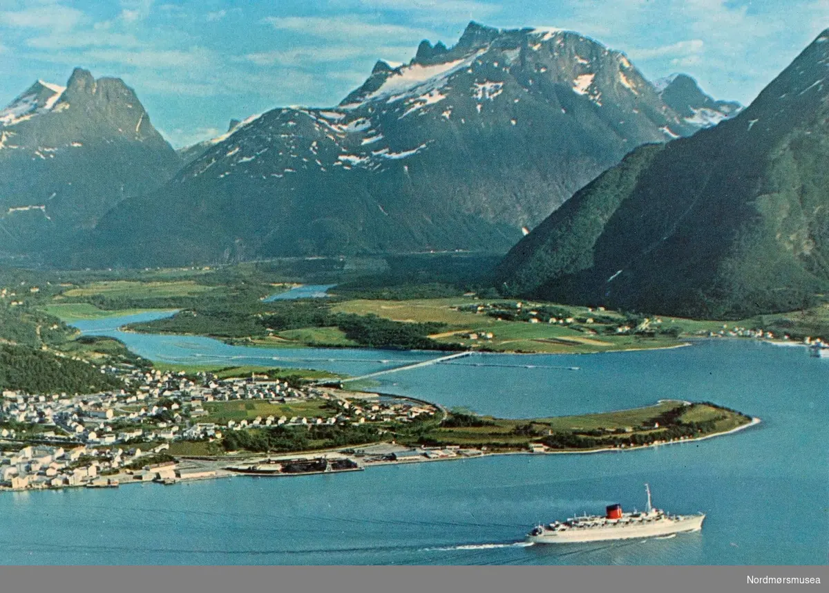 Postkort ";1612/25"; med motiv fra Åndalsnes og Veblungsnes, med Romsdalshorn og Trolltindene i bakgrunnen. Kortet er utgitt av Mittet &amp; Co. A/S. Fra Nordmøre Museums fotosamlinger. Reg: EFR

