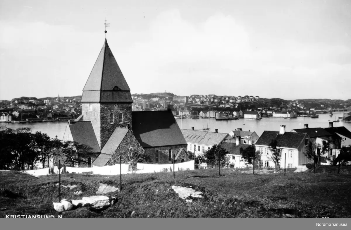 Postkort med motiv av Nordlandet Kirke, som ligger på Nordlandet i Kristiansund. I 1875 besluttet bystyret i Kristiansund å bygge en kirke i denne bydelen. Det ble sikret tomt i 1883, og grunnsteinsnedleggelsen fant sted den 4. mars 1913. Nordlandet kirke ble innviet 16. desember 1914. Kirken ble tegnet av kirkearkitekt H. Schytte-Berg fra Trondheim, etter en arkitektkonkuranse mellom arkitektene H. Skytte-Berg, O. Stein og Kr. Rivertz. Rivertz står for kjente bygg i Kristiansund som Festiviteten, Norges Bank og byens nye jugenstilpregede Grand Hotell, da det første Grand Hotell brant ned i 1907. Byggmester Havnes fra Ålesund, stod for Hovedentreprisen. Mer om Nordlandet kirke kan leses her: http://kristiansund.kirken.no/tekstsider.cfm?avdelingsid=38517&amp;text_id=49401. Fra Nordmøre Museum si fotosamling
