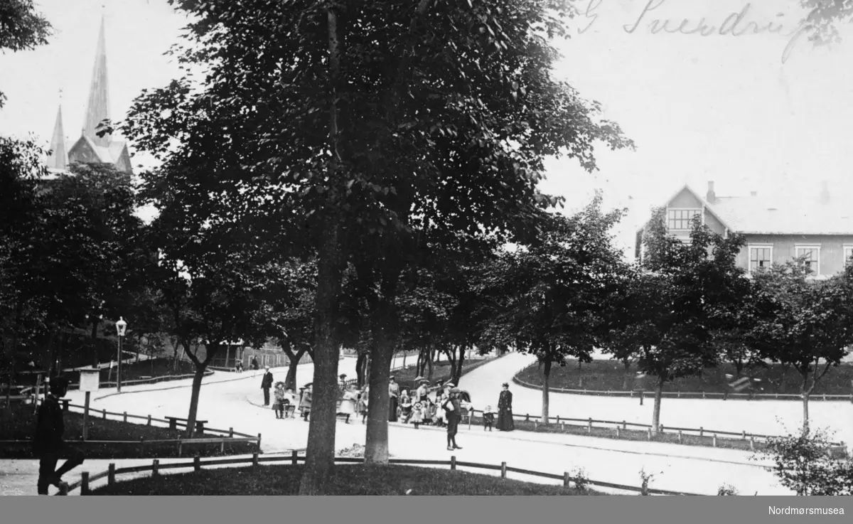 Postkort med motiv fra parken ved Parkveien/Langveien på Kirkelandet i Kristiansund, hvor vi ser litt av Kirkelandet kirke på Lyhshaugen til venstre, samt litt av den Høgre Offentlige skole til høyre. Bildet er trolig datert til perioden 1930 til 1939. Fra Nordmøre Museums fotosamlinger. Reg: EFR
