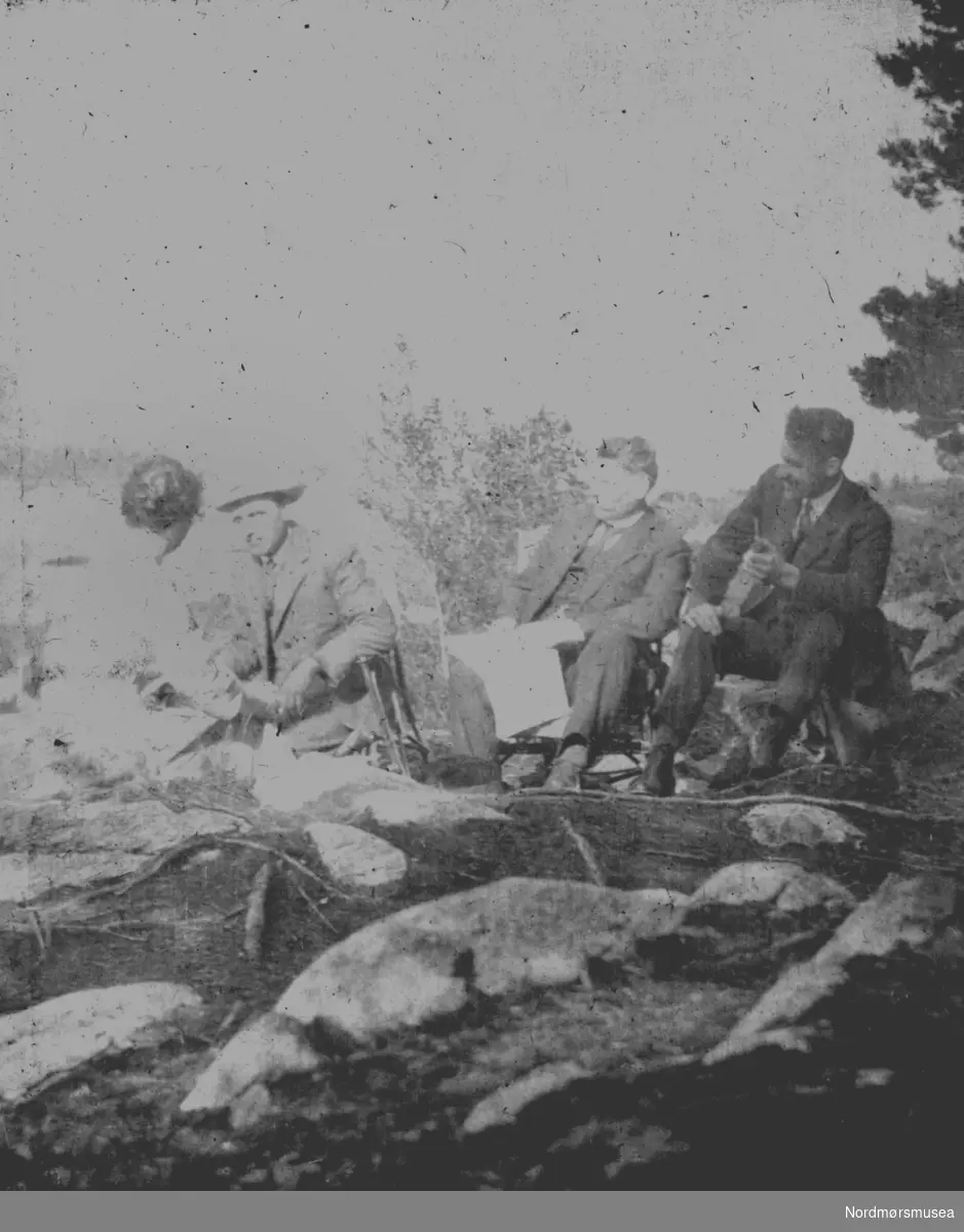 Foto av tre menn og en kvinne trolig på landtur. Det er ukjent hvem vi ser på dette svakt ødelagte bildet, samt hvor og når bildet er tatt.
Fra Nordmøre museums fotosamlinger.
