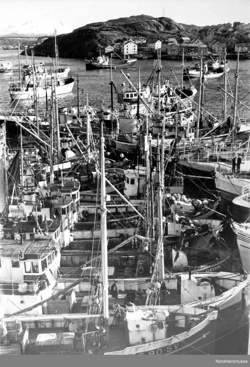 Foto fra Vågeveien på Kirkelandet i Kristiansund, hvor båtene ligger tett i tett og ved siden av hverandre. Bjørnehaugen i bakgrunnen. Det er storsildfiske i Kristiansund. Bildet er datert 1963, og er fotografert fra området rundt Gullagården. I bakgrunnen ser vi Nordsundbroen helt til venstre, som knytter Nordlandet (til høyre) og Gomalandet (utenfor bildet til venstre) sammen. Fotograf og giver er Kjell Sandum i Adresseavisen. Fra Nordmøre Museums fotosamlinger.