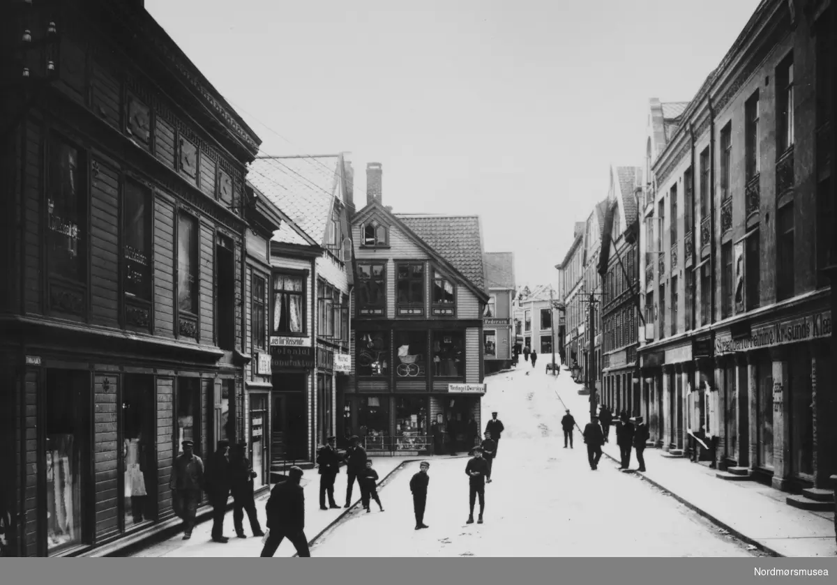 Storgata, sett fra hjørnet til det daværende ";Kaibakken";. skilt
 Fra Nordmøre Museums fotosamlinger. Tilleggsinfo: Dette bildet må tidligst være tatt i 1908. Første bygningen til høyre, Kristiansund forretningsbank, ble bygd etter at Bejergården ble revet i 1908(1910). Den sto lengre ut i gateløpet, slik at vi i denne vinkelen ikke kunne se Storgata fra det smalere partiet midt i bildet. Ref. bildet fra ca 1905, med den gamle gården: http://www.fylkesarkiv.no/foto/detalj?http://www.sffarkiv.no/sffbasar/default.asp?p=result&amp;ptype=single&amp;db=dbfoto&amp;sql=sfffoto%20=%20%27FAKf-100296.183996%27. (Informant: Tor Arne Skålvik.)



