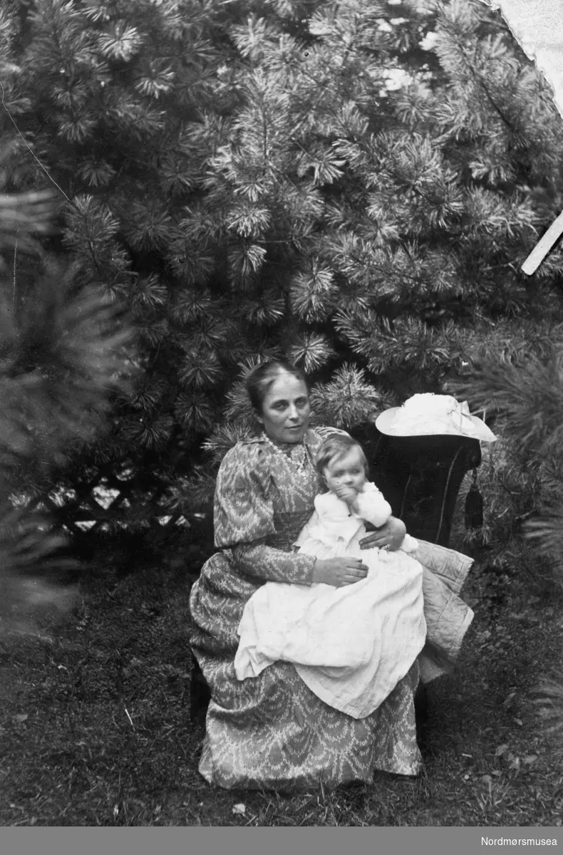 Portrett av en ukjent kvinne, trolig fra Kristiansund, eller med tilknytning til Nordmøre. Datering og fotograf er ukjent. arrangert bilde med tung stuestol og poserende hatt.- Fra Nordmøre Museums fotosamling.
