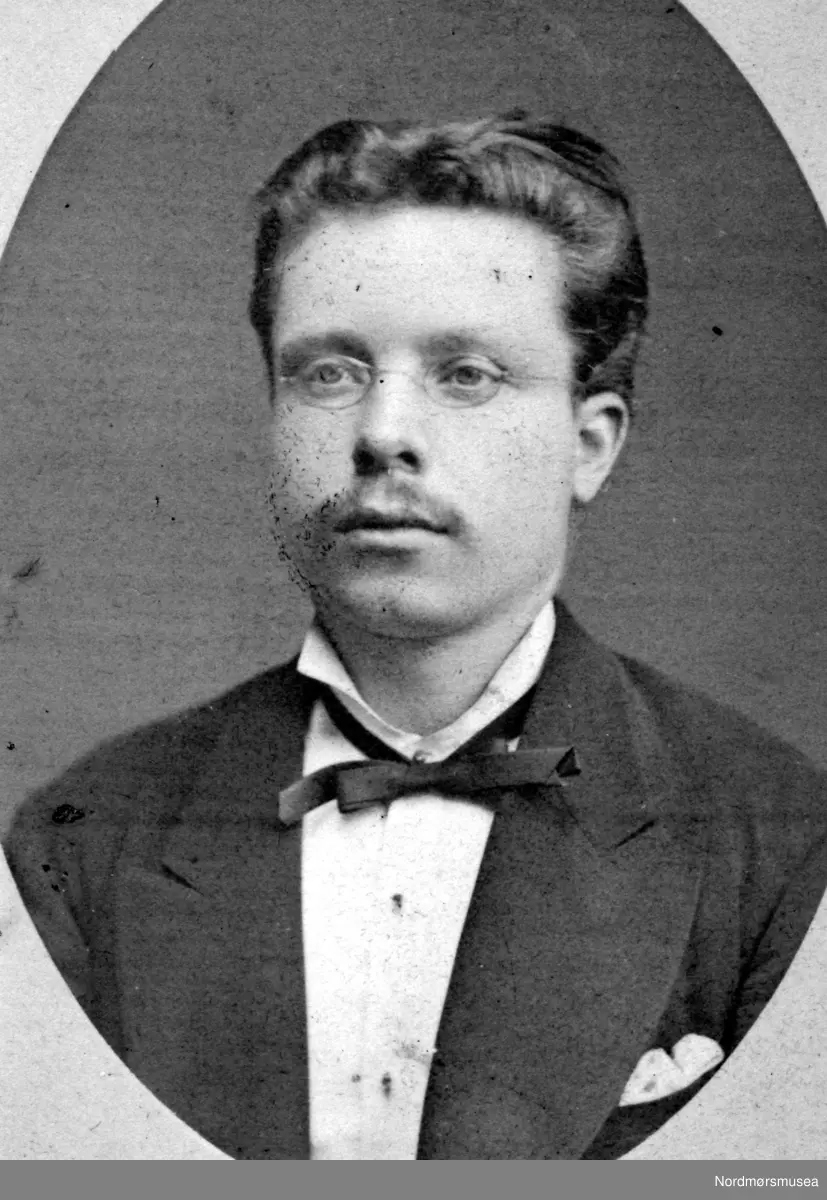 Portrett av Oscar Clausen (1849-1890), sønn av konsul og kjøpmann i Kristiansund, Hans Clausen og kone Caroline Sophie Walther. Oscar var handelsborger og agent i byen og ble gift med Kathinka Edvarda Wilhelmine Selmer. (Info: 
Randi Elisabeth Hagen)  Kristiansund omkring århundreskiftet 1870 - 1890. Fotoet er fra ett av flere album tilhørende Ida Knudtzon, med bilde fra KMb-1999-007.0151 til KMb-1999-007.0270. Fra Nordmøre museums fotosamlinger.