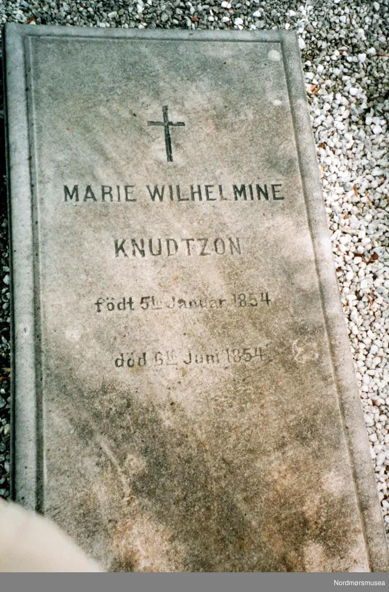 Gravstøtten til Nicolay Heinrich Knudtzon III og Marie Wilhelmine Knudtzon's barn nummer tre som døde som spedbarn.  Hun var oppkalt etter moren og var født 5. januar 1854 og døde 6 måneder senere; den 5. juni 1854. Fru Marie Wilhelmine Knudtzon var Nicolay H. Knudtzon III's første kone. Da hun døde i 1871 giftet han seg på nytt med Caroline Werring. Fra Nordmøre Museums fotosamlinger. 