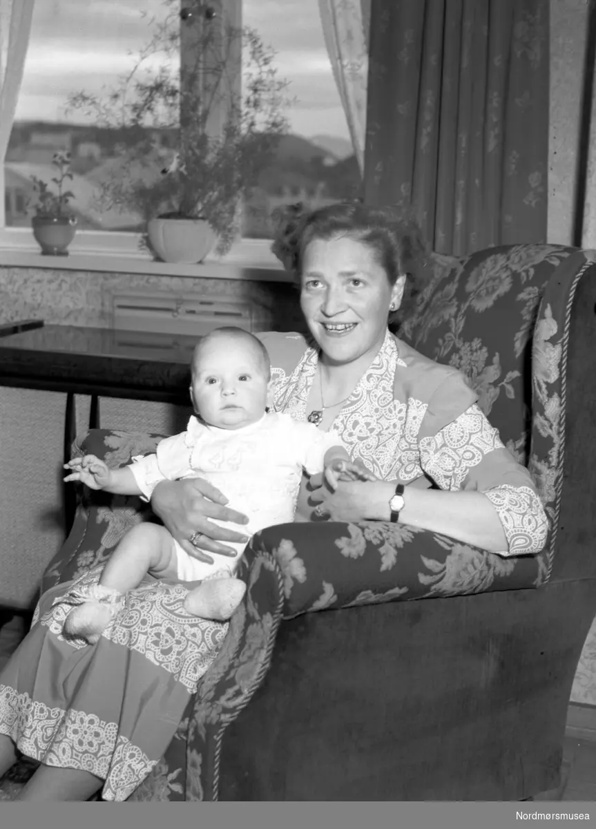 mor og barn variant 3. -  NB Bygningen har sentralfyring. Se varmluftsautomaten under vinduet. Kan være i Storgata, med utsikt mot Innlandet.  Fra Nordmøre Museum sin fotosamling, Williamsarkivet.
