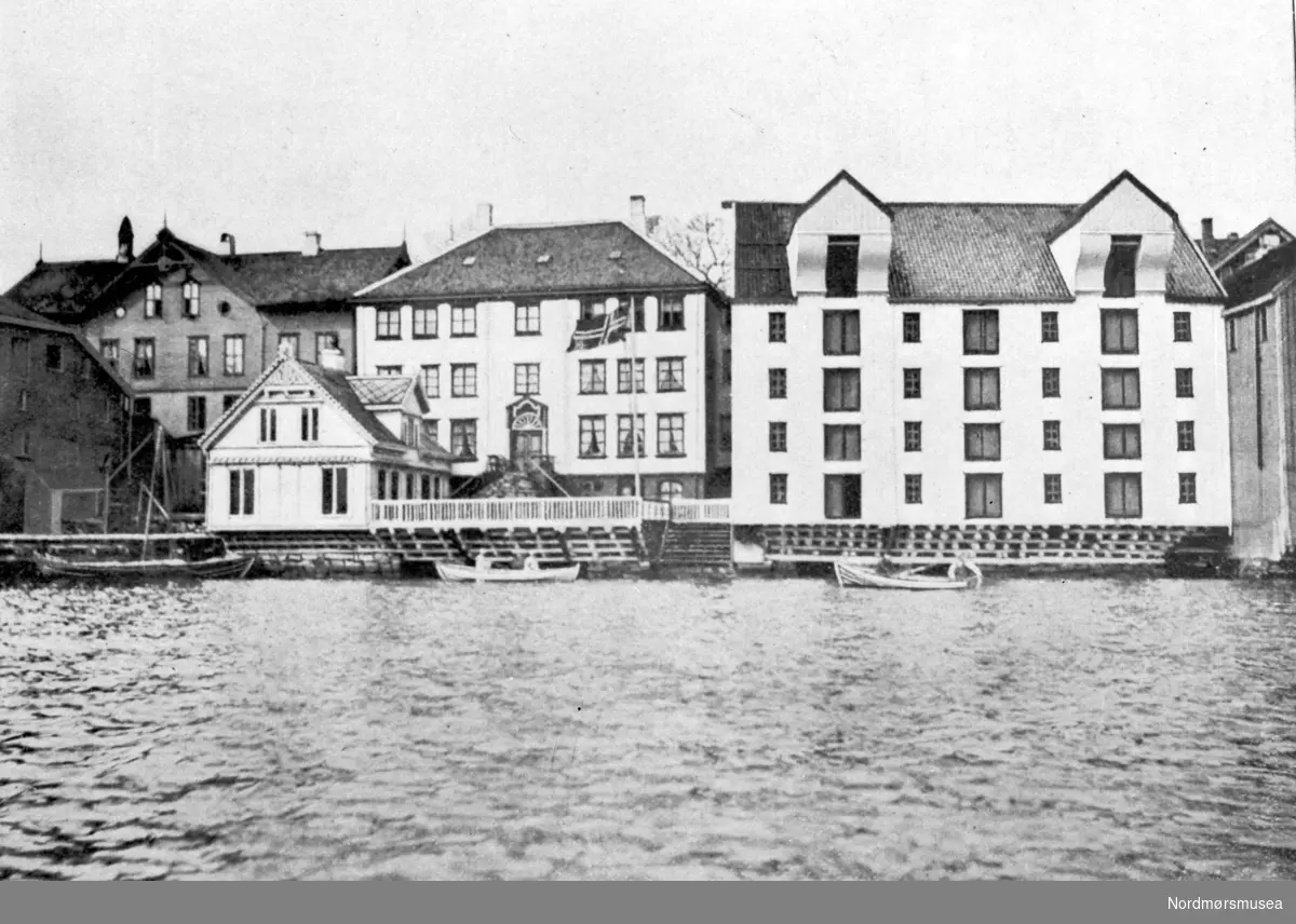 Motivet er kjøpmann og konsul Nicolay Henrich Knudtzons bolig, med kontorbygningen til venstre og hjemmebrygga til høyre, ved havna i Kristiansund.
 Lengst til venstre i bakgrunnen ligger boligen som var eid av kjøpmann F. N. Volckmar. Alt brant i 1940. Fra Nordmøre Museum sin fotosamling, Williamsarkivet.
