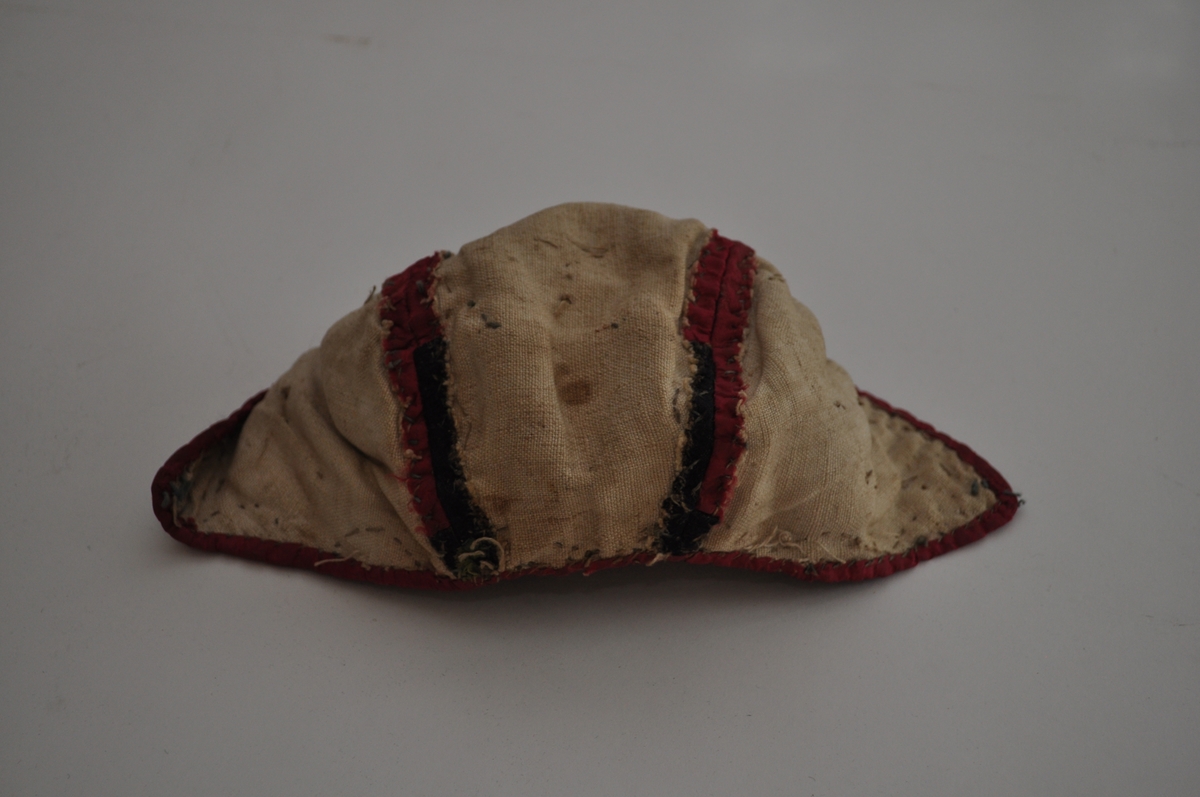 Lua er ei trebladlue med to speilvendte sidestykker og et tilnærmet rektangulært midtstykke. Hovedstoffene er av silke, sydd sammen av 15 biter. Tre biter er av lys, blågrøn silke, hvorav en bit har brosjert blomster- og bladmotiv. Fem biter er svarte, hvorav en bit har brosjert mønster i gult og grønt. Sju biter er av cerisse-rød silke, hvorav minst to er av damask. Langs kantene, sømmene og øverst på sidestykkene er lua dekorert med en blonde av hvit og grønn silketråd. På hvert sidestykke er fem små cerisse-røde silkebiter sydd fast. Ytterligere en er sydd på midtstykket bak, og det er rester etter minst en til samme sted. I skjøten mellom tre stoffbiter på midtstykket bak er det sydd på en trådrosett av lyserød og grønn silketråd, av samme materiale og type som på henglene registrert som OT.5342 AB. Lua er fôret med ubleiket linlerret, stykkene er sydd sammen og sårkantene kastet over til hver side, synlig på vranga. Framkant og nederkant er dekket av cerisse-rød silke, sydde til med lyseblå silketråd. Det er trådspor etter knyteband i lua.