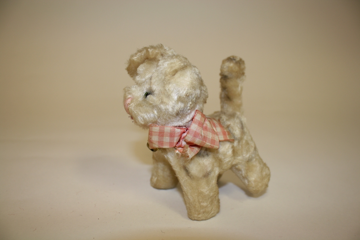 Gitt av Lisbeth Andreassen Chumak. Liten katt med rutete sløyfe med bjelle. Fra 1950-tallet. Beigebrun farge på katten. Opprinnelig hvit.