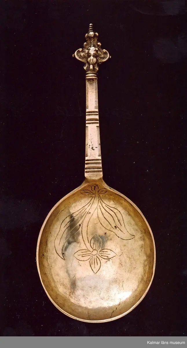 KLM 3010. Sked. Av silver. Renässanstyp kerubsked, med runt blad, kort, platt skaft slutande med en kerubknopp. Blad med graverad dekor, en blomma. Stämplar: stadsstämpel Vimmerby; mästarstämpel L.C. för Lars Castman 1739-1784; årsstämpel saknas.