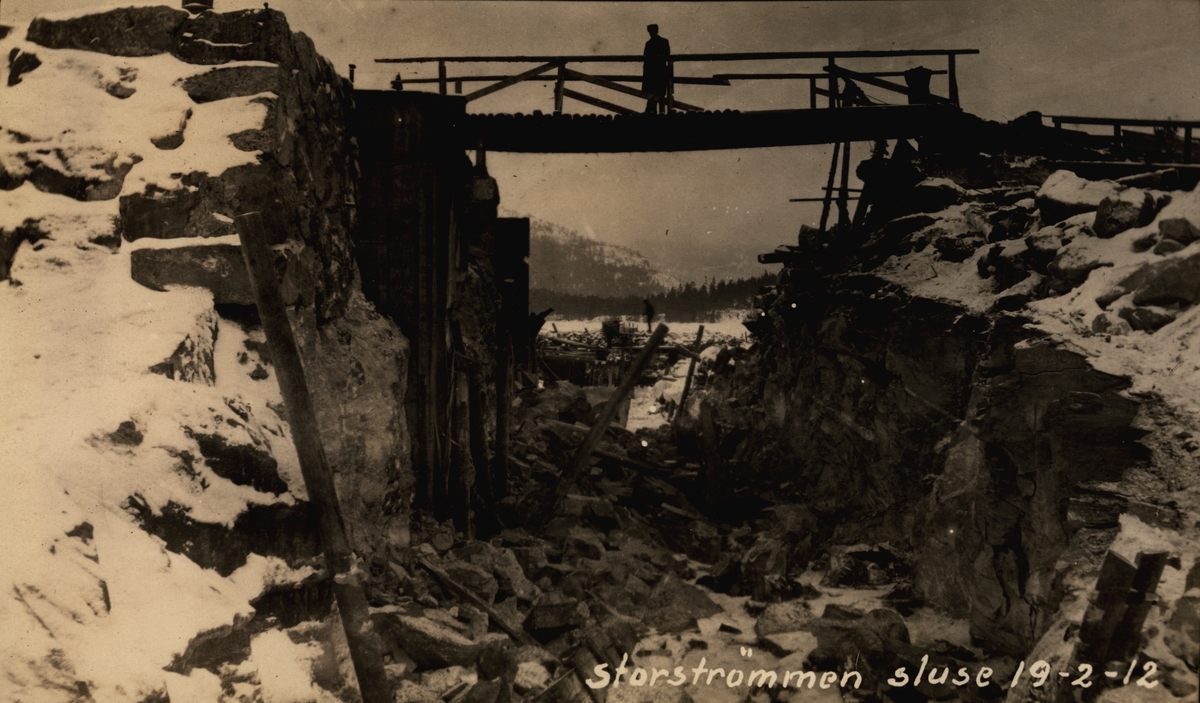 Storstrømmen sluse. Kanalen etter sprenging. Vinter og snø. Fjell og skog i bakgrunn. Mann på bro. (Arkiv: Kanalvesenet/Vassdragsvesenet Uba-2-08)