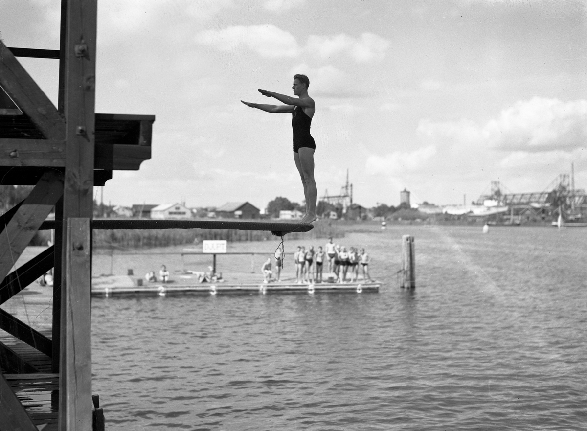 Bildserie från slutet av 1930-talet från Karlstads dåvarande simstadion. Anläggningen låg i anslutning till den s k badholmens östra sida söder om Kanikenäset. Badet invigdes 1923 och togs ur bruk och revs 1943 pga dålig vattenkvalité. En liknande konstruktion som ersatte den på bilderna byggdes upp i Örsholmstjärnet i början av 1950-talet.