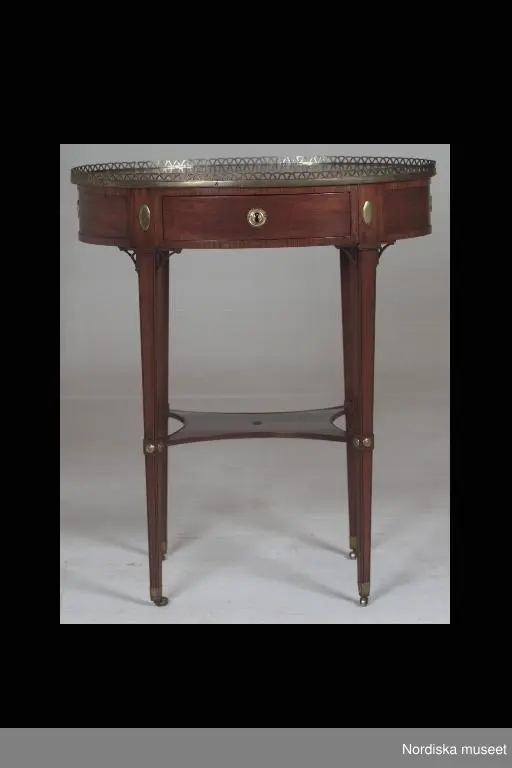 Huvudliggaren:
"Sybord, sengustavianskt. Blindträ: furu. Fanerat med mahogny. Skivan oval med mässingsgaller helt av mahogny. 1 låda, al och furu, fanerad med mahogny. Fyra avsmalnande ben med hyllskiva. Sign på lådans botten: Fred. Schalin. Snickare och Schatullmakare. h 79, l 66, br 46 cm."