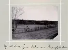 Bildserie tagen av August Malmborg (1875-1895), son till landshövding Adolf Malmborg, ägare till Våxnäs herrgård, och hans maka Julia, född Åkerhielm.  Bilderna är tagna från tidigt 1890-tal fram till 1895 med texten skriven av modern: Vy vid landsvägen söder om Bryngfjorden.