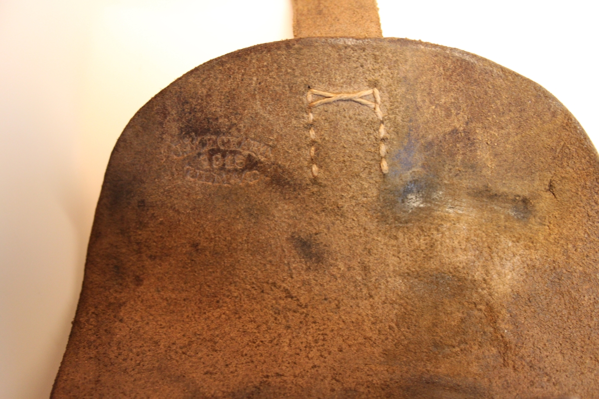 Hylse i brunt lær med lukning høyre side. Lukker ved hjelp av rund knapp i spor. Sydd.

Egen lomme høyre side til ekstra magasin. Ekstra magasin ligger i. 

Hylse har stempel på innsiden av lokk: 
Vanskelig å lese men er bokstaver og tall. Ovalt stempel.

Venstre side har feste til belte. Beltet tres da gjennom feste. Sydd på i samme lær som resten.