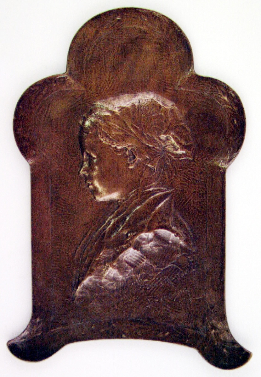 Relief i brons med profilporträtt av ung kvinna från Bretagne. Gjuten hos Herman Bergmans Bronsgjuteri i Stockholm.