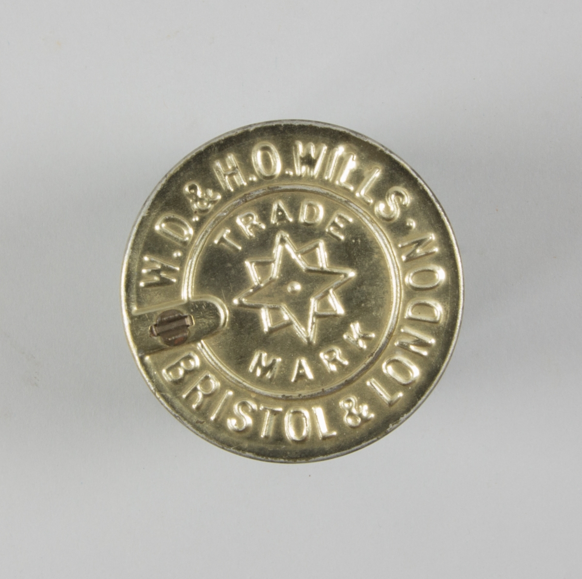 Burk, cylindrisk, av plåt med plant avtagbart lock. Präglad text på locket. Runt burken påklistrad pappersetikett. Burkens insida pappfodrad. Burken innehåller fem cigaretter.