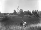 Pojke paddlar kanot utanför Hamrånge kyrka.