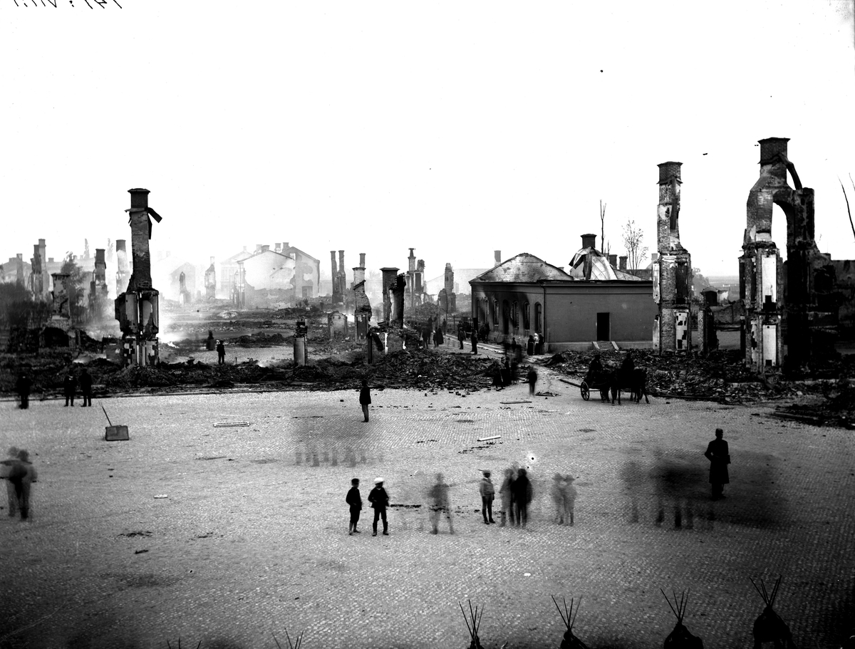 Branden i Köping 1889. Fotografi från norra sidan av Stora torget mot söder. Till höger står enbart skorstenarna kvar av Havreettan Eriksson, bortom denna Mälarbankens byggnad som också är utbränd. Enbart grunderna står kvar av kvarteret längs med södra sidan av torget.