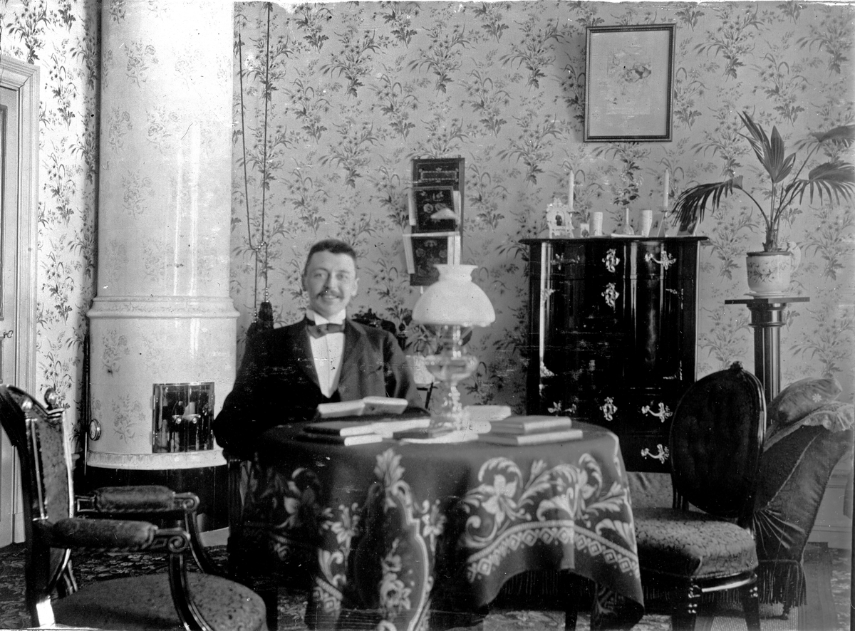 En man som sitter vid ett bord och läser. Fotograf Alfred Bergendahl. Givare H Bergendahl.