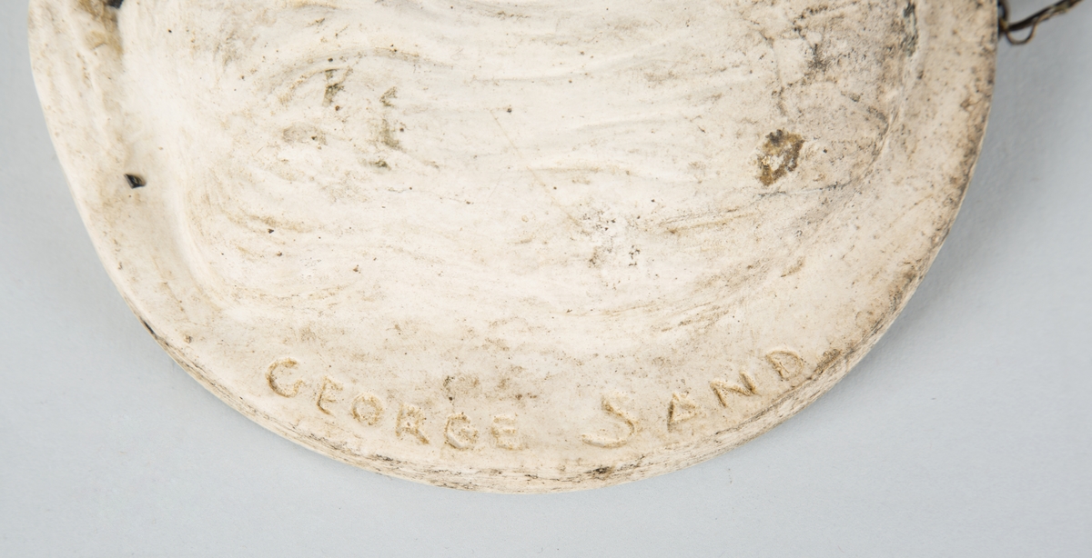 Relieff av George Sands hode i profil (venstre). 