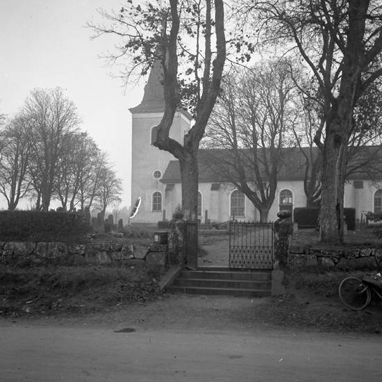 Berga kyrka, Lagan. I förgrunden syns en stenmur med grind.
