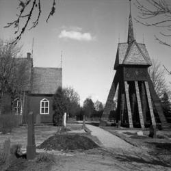 En träkyrka med klockstapel till höger. 
Tutaryd.