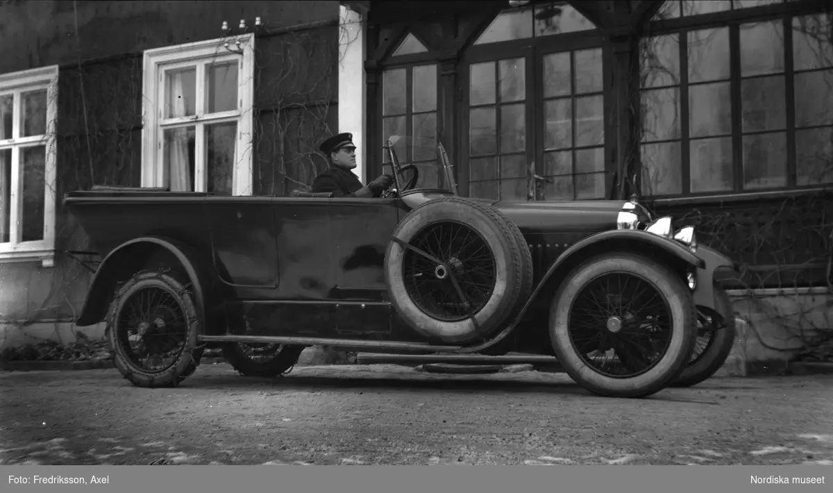 Svante Hammarbäck, greve Clarence von Rosens chaufför på Väsby. Chauffören sitter i bilen som står parkerad framför boningshuset.