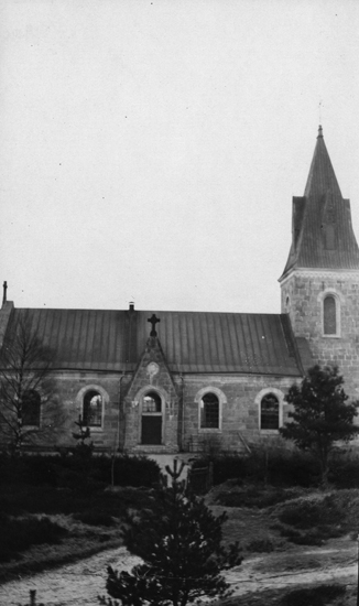 Foto på en kyrka med en gran längst fram.
